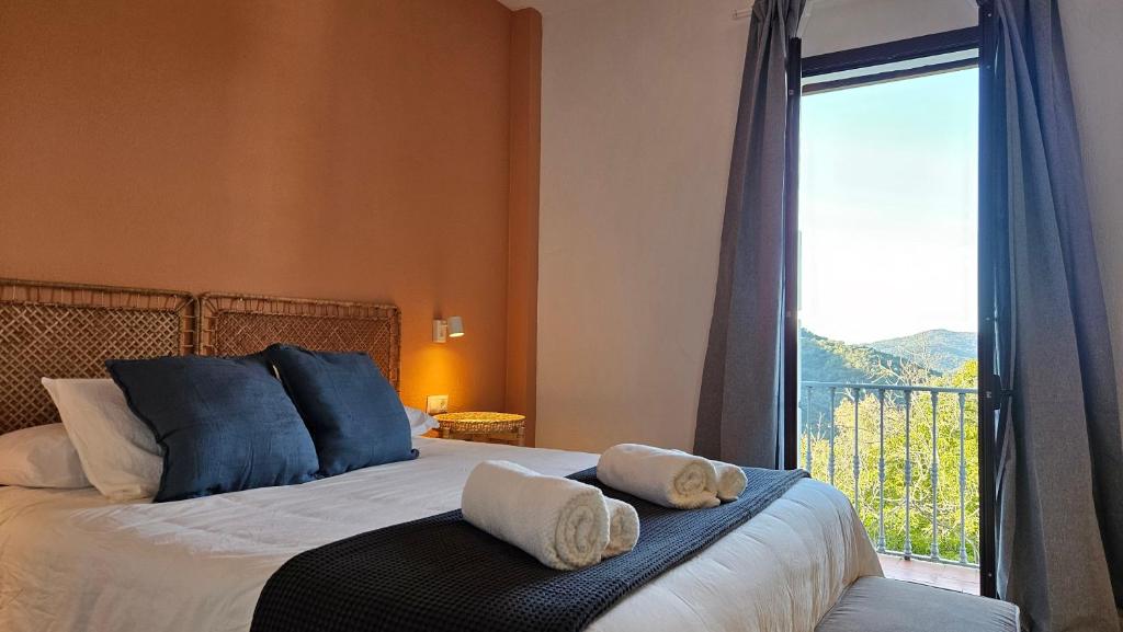 a bedroom with a bed and a large window at Hotel Rural Mirador de Jubrique in Jubrique