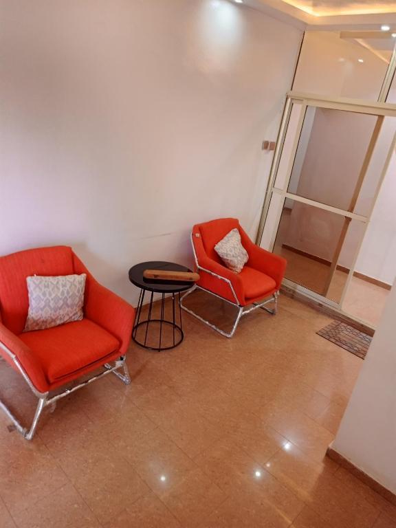 two red chairs and a table in a room at TheGeneral Place in Ikorodu