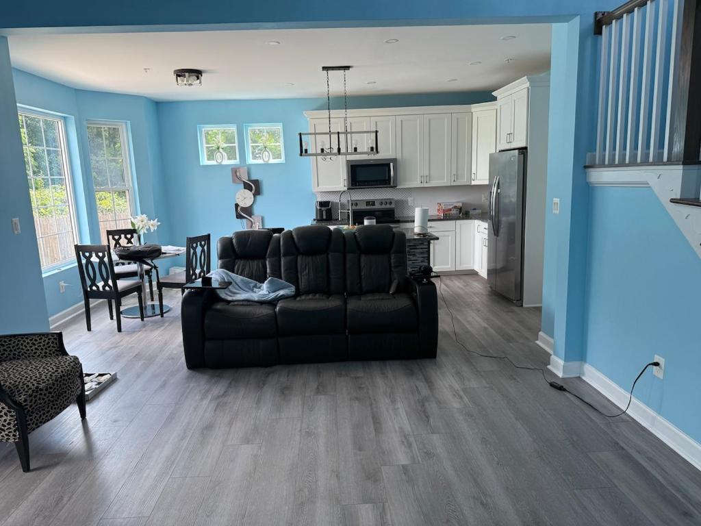 a living room with a black couch and a kitchen at Work and play close to everything in Frederick