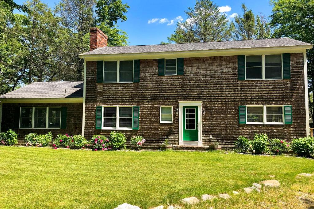 a brick house with a green door and a yard at Private Waterfront Retreat in Edgecomb