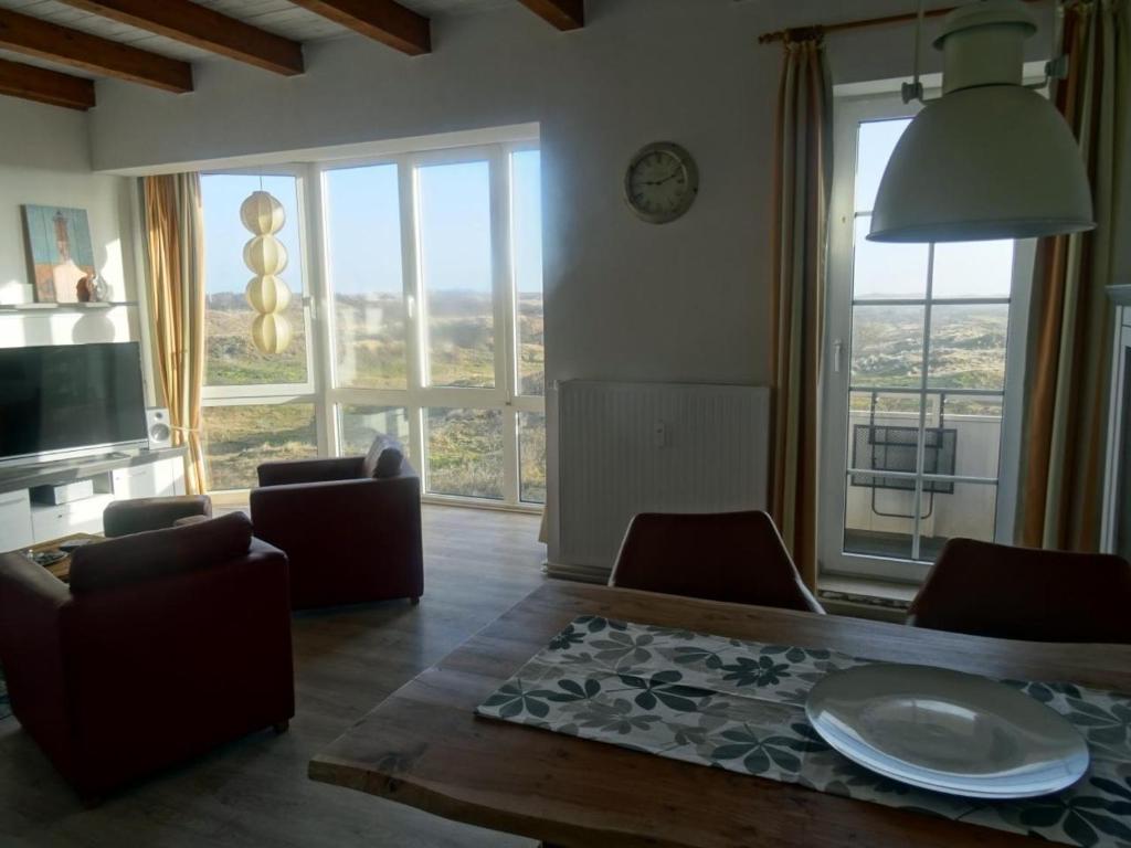 un soggiorno con tavolo, sedie e finestre di Ankerplatz im Strandschlösschen a Baltrum