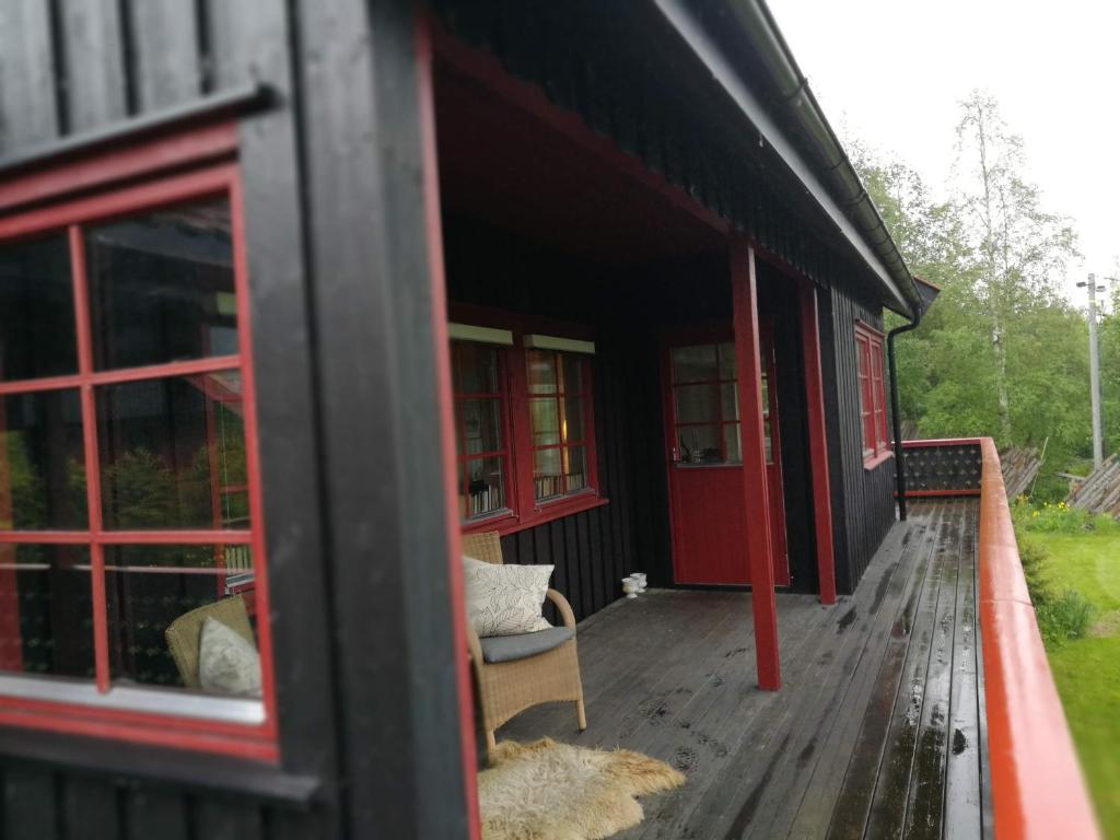 a house with a porch with a chair and windows at Skap Opplevelser in Svingvoll