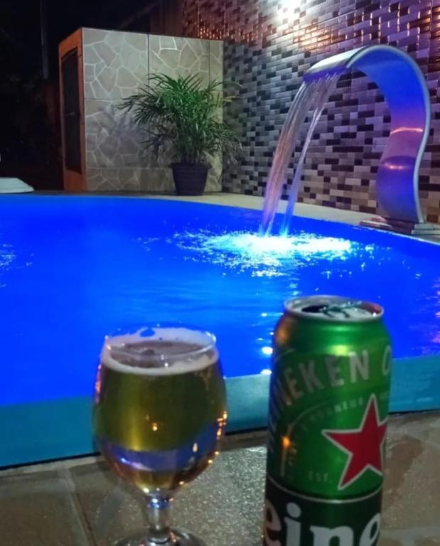 a bottle of beer and a glass of wine in front of a pool at Bella casa de praia in Araruama