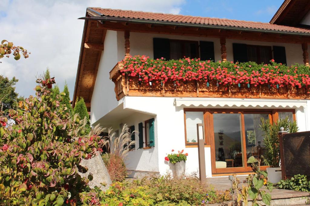 a house with red flowers on a balcony at Abendsonne in Lechbruck