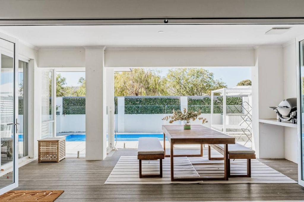 ein Esszimmer mit einem Tisch und einem Pool in der Unterkunft Sundrift - Sophisticated Beachside Retreat with Pool in Dunsborough