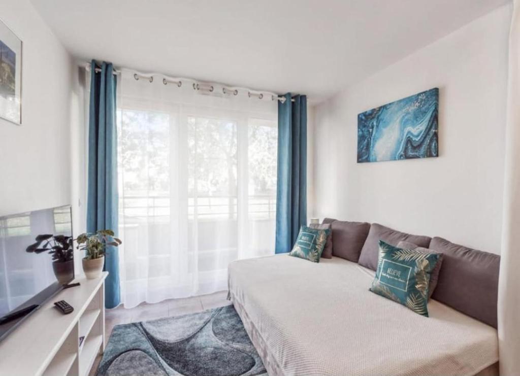 a living room with a couch and a large window at Apt au calme, 2-3 chambres, Sauna, 2 parkings, bus sur place in Montévrain