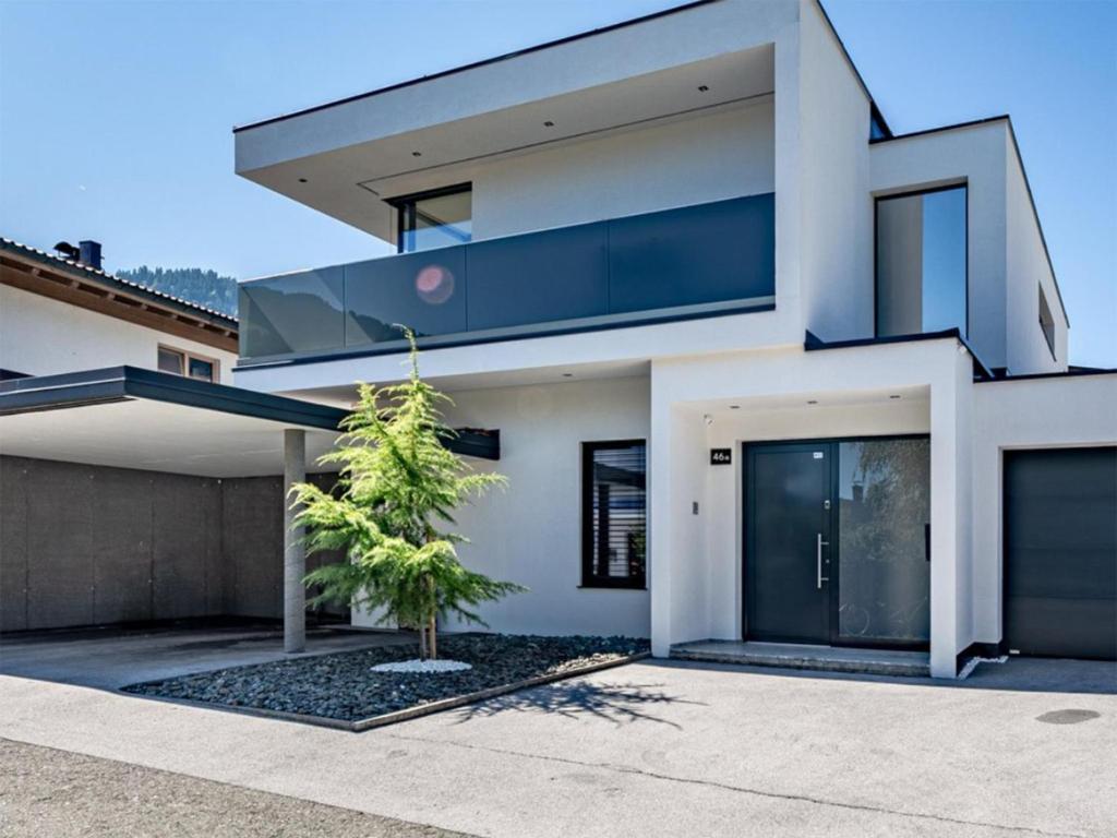 a white house with a tree in front of it at Alpin Chalet ARTE in Söll
