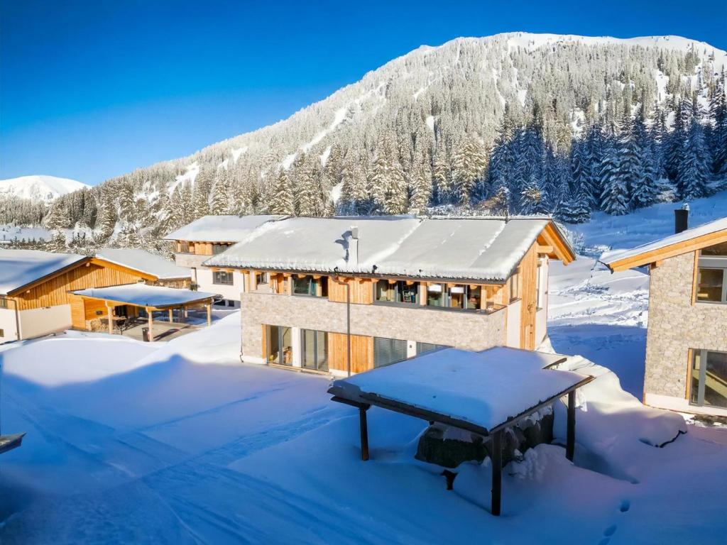 a house in the snow with a mountain in the background at Grebenzen Lodge Edelweiss in Sankt Lambrecht