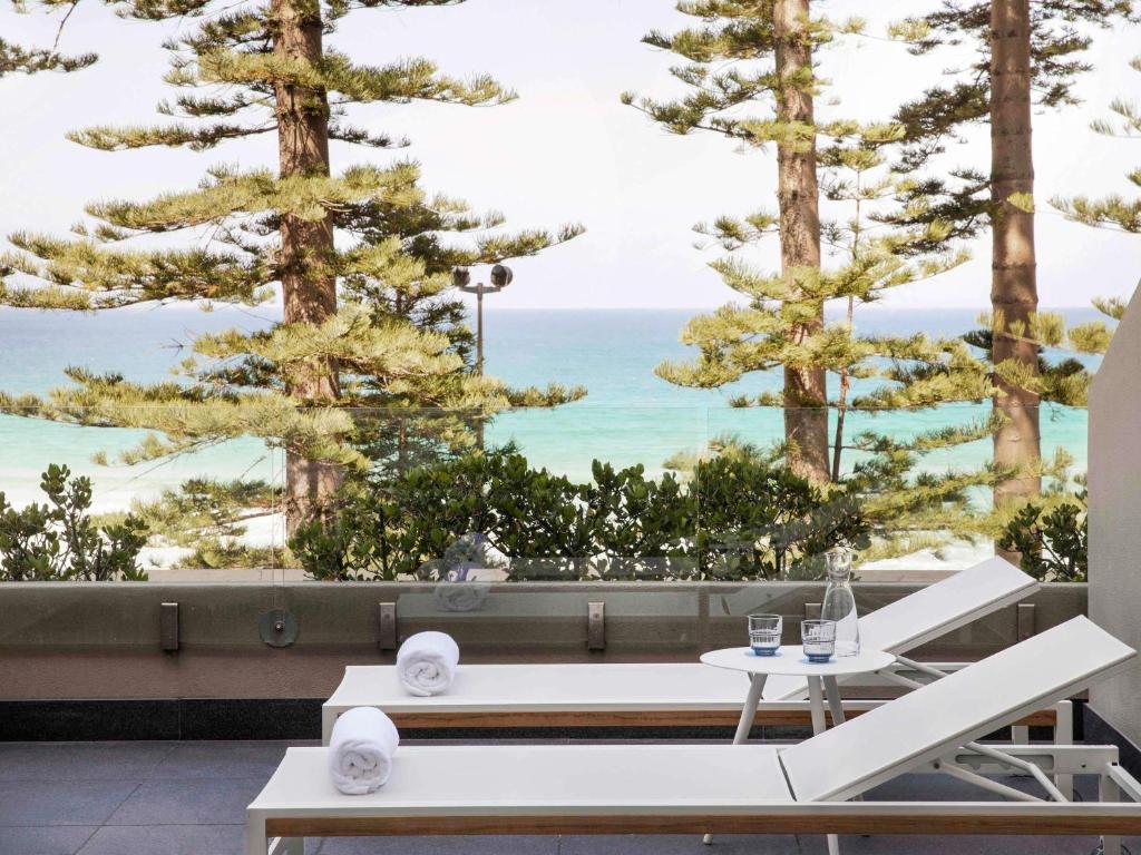 a view of the ocean from a patio with trees at Manly Pacific Sydney MGallery Collection in Sydney
