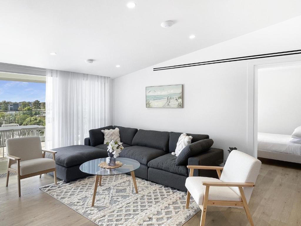 ein Wohnzimmer mit Sofa und Tisch in der Unterkunft Modern 4-Bed Townhouse with Water Views in Malua Bay