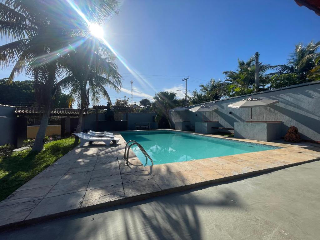 a swimming pool in a yard with palm trees at Pousada Areia in Saquarema