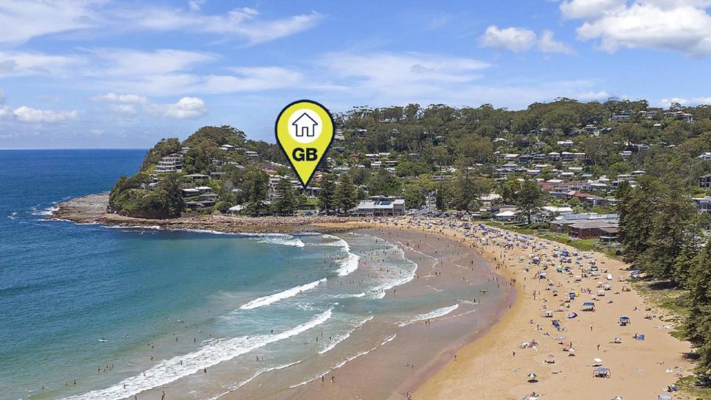 a large yellow kite flying over a beach at The Point On Cliff - Two Levels and Views in Avoca Beach