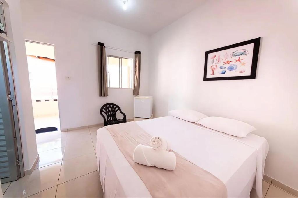 ein weißes Schlafzimmer mit einem Bett und einem Handtuch darauf in der Unterkunft Fonte dos Corais - Suíte Lua na Praia in Maragogi