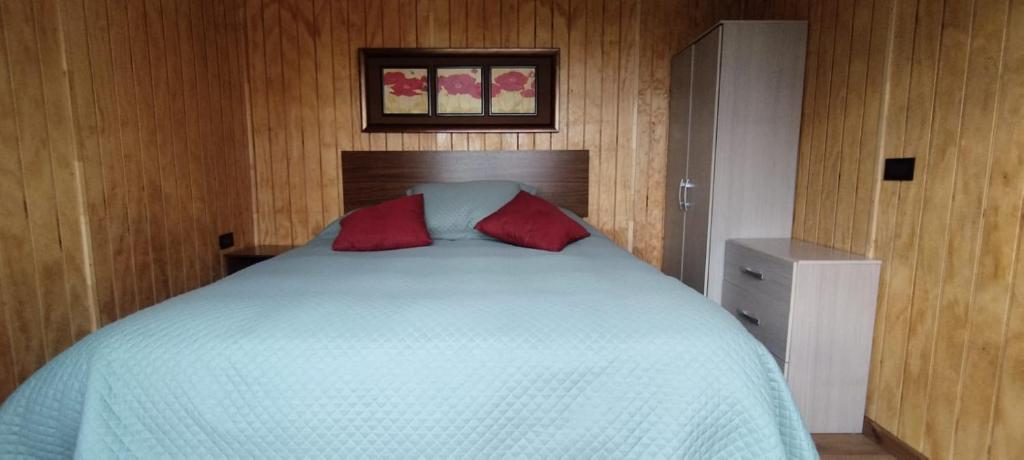 une chambre avec un lit avec deux oreillers rouges dessus dans l'établissement Cabañas La Patagona y el Chilote, à Llau-Llao