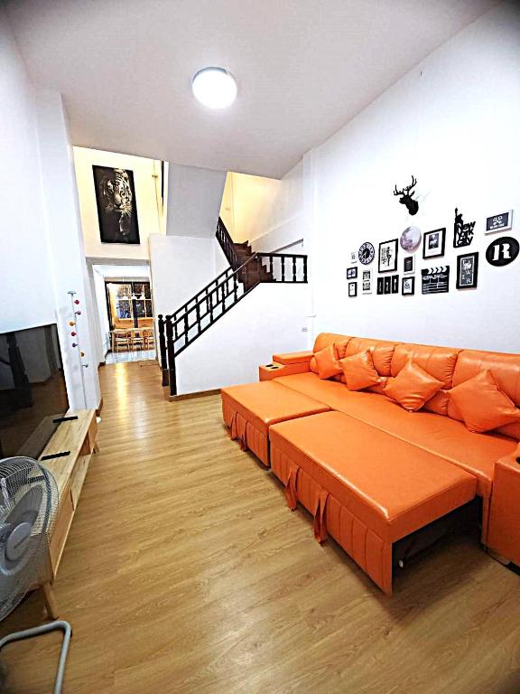 a living room with an orange couch and a staircase at A Day Home in Chiang Mai