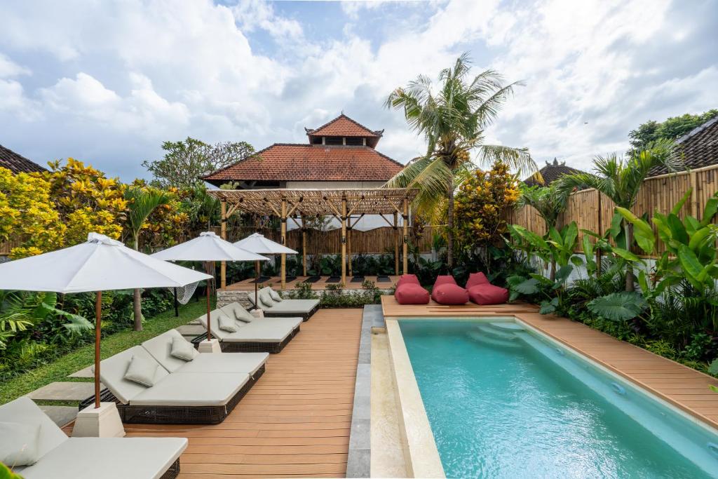 a pool with chaise lounge chairs and a gazebo at Palermo Suites by Betterplace in Ubud