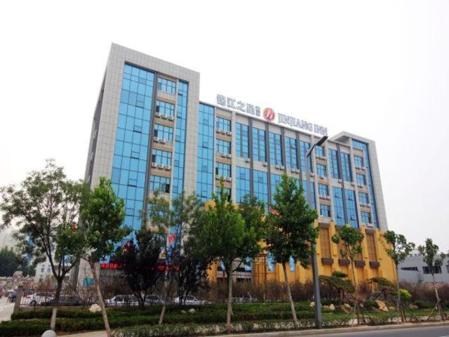 un gran edificio azul con árboles delante de él en Jinjiang Inn Select Yantai Development Zone Wuzhishan Road, en Yantai