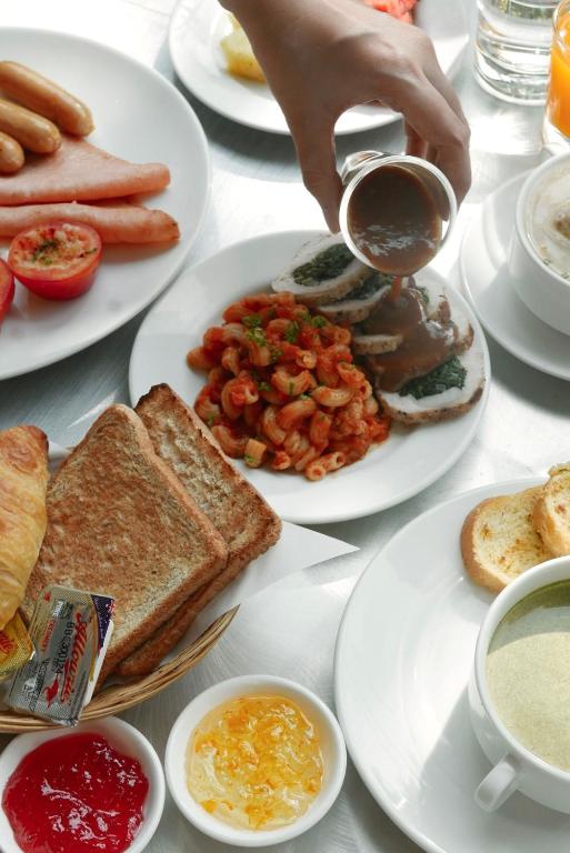 A close-up breakfast spread of toast, sausages, eggs and pasta.