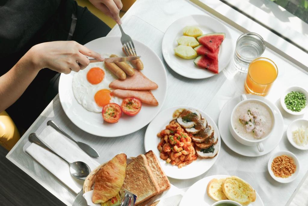 A plated breakfast spread with eggs, sausages, fruit, toast, juice, and porridge.