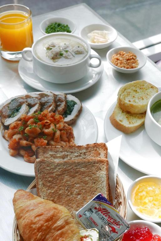 A close-up breakfast spread with soup, toast, pastries, seafood, fruit and juice.