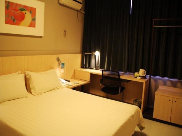 una camera d'albergo con letto e scrivania di Jinjiang Inn Zhengzhou Dashi Bridge a Zhengzhou