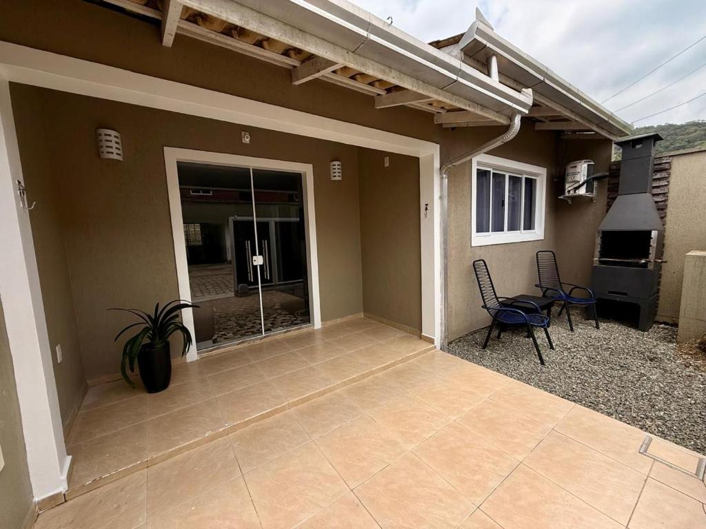 eine Terrasse eines Hauses mit Stühlen und einem Grill in der Unterkunft Casa charmosa praia Itapema in Itapema