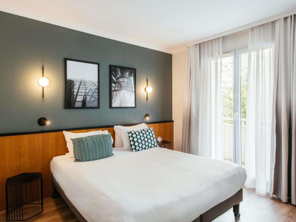 a bedroom with a large bed and a large window at Aparthotel Adagio La Défense Le Parc in Courbevoie