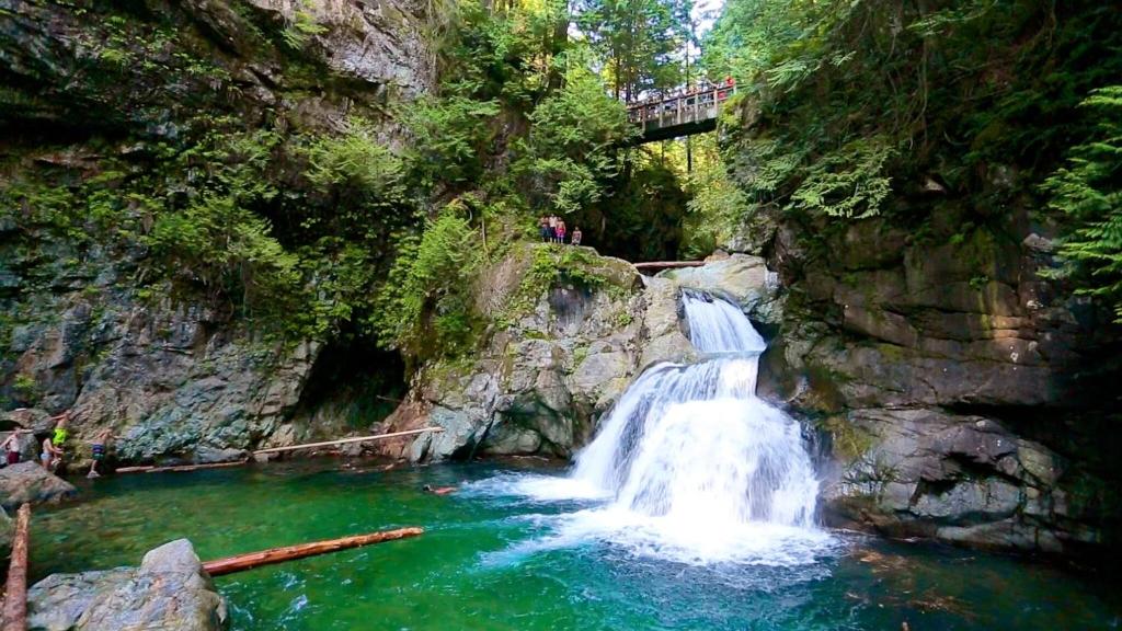 een waterval in een rivier met een brug erover bij Modern 2Bed Suite Near Capilano Bridge & Trails in North Vancouver