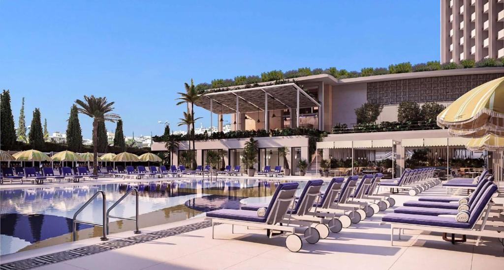 a resort with a pool and chairs and a building at Conrad Athens The Ilisian in Athens