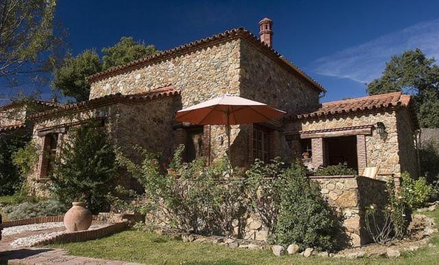 a stone house with an umbrella in front of it at Gîte El Conejo in Alájar