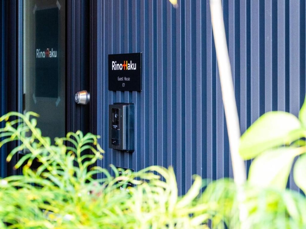 a sign on the side of a blue building with plants at Rino-Haku 01 in Anan
