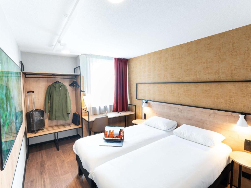 a hotel room with a bed and a television at Ibis Orleans La Chapelle Saint Mesmin in La Chapelle-Saint-Mesmin