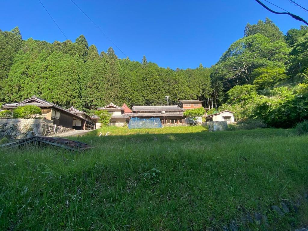 a house in the middle of a field of grass at OldJapaneseHouseintheMountains山の中の築100年古民家赤目のやど in Nabari