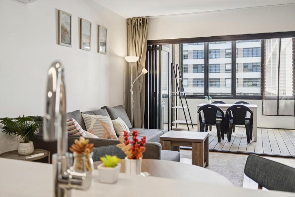 ein Wohnzimmer mit Sofa und Tisch in der Unterkunft Bright 1BR Apartment in the heart of Dickson in Downer