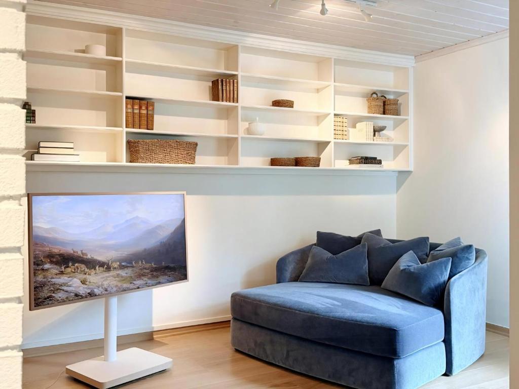 a living room with a blue couch and shelves at Villa With Architect-Designed Garden In Alsvik in Sørvåg