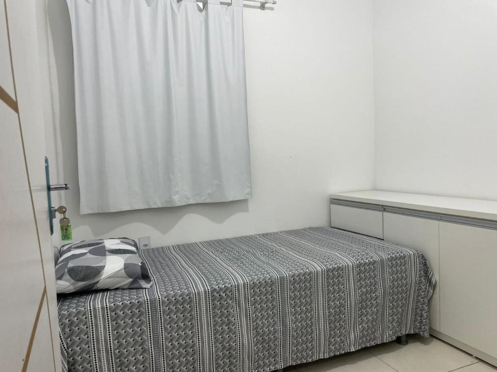 ein Schlafzimmer mit einem Bett mit einer grau-weißen Decke in der Unterkunft Fênix in Manaus