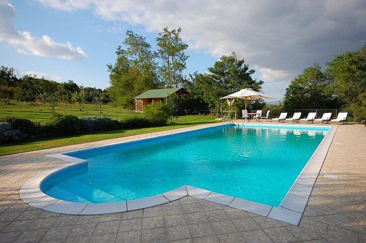 Una gran piscina con sillas y una casa. en Casa Verde, en San Michele in Teverina
