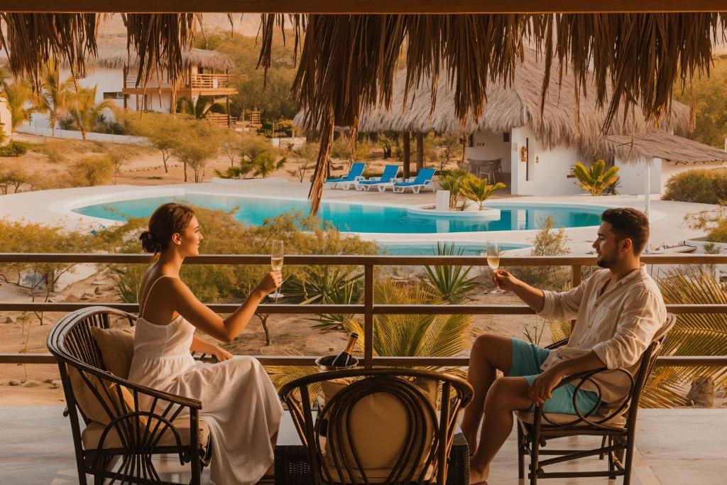 Ein Mann und eine Frau sitzen auf Stühlen mit Weingläsern. in der Unterkunft Beach Home Organos Piura Family Vacations in Los Órganos
