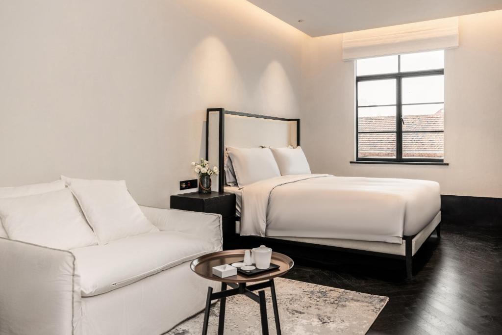 Un dormitorio blanco con una cama y un sofá. en 烟台朝阳文保艺术酒店, en Yantai