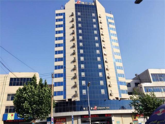 un grand bâtiment avec des fenêtres bleues dans une ville dans l'établissement Jinjiang Inn Zibo Zichuan Tongqian Square, à Zibo