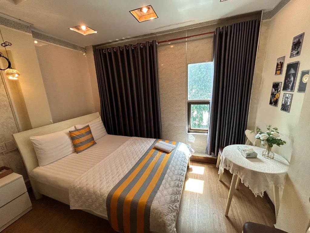 a bedroom with a bed and a table and a window at Jewel Hotel in Ho Chi Minh City