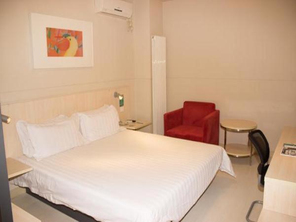 a bedroom with a white bed and a red chair at Jinjiang Inn Wafangdian Xichangchun Road in Wafangdian