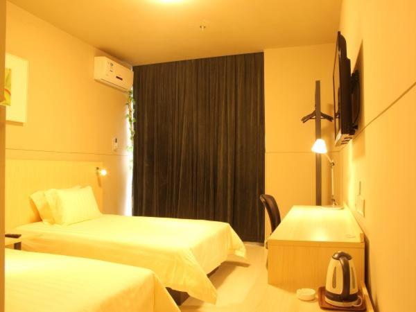 a hotel room with two beds and a television at Jinjiang Inn Suzhou Shihu International Education Park in Suzhou