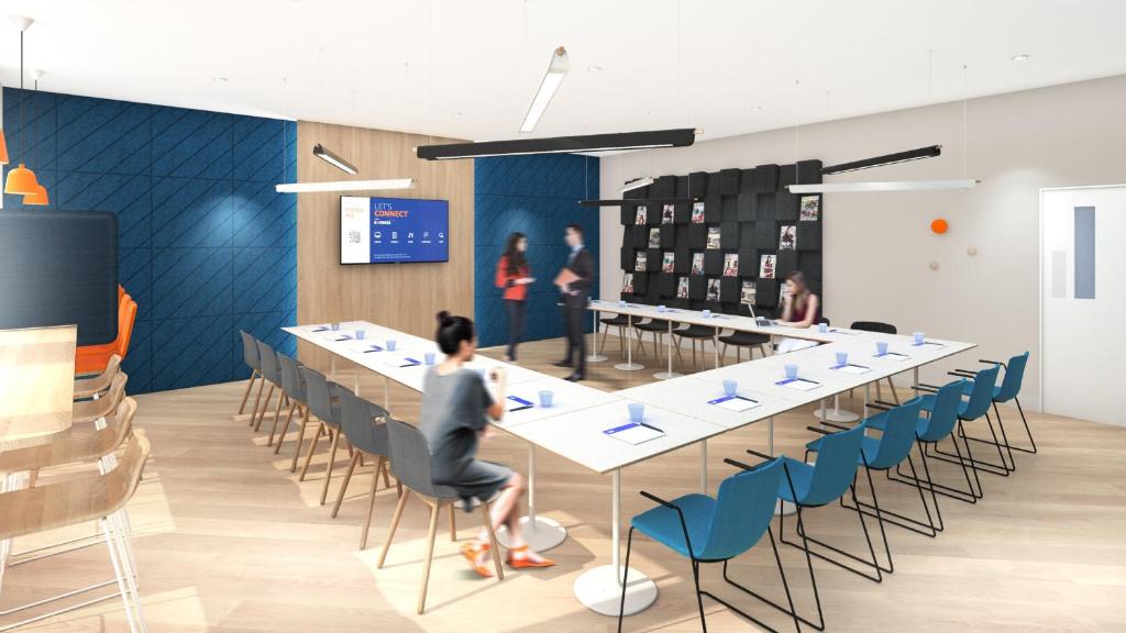 Holiday Inn Express Shenzhen Sports Center by IHG في شنجن: شخص يجلس على طاولة طويلة في غرفة