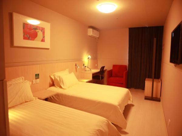 a hotel room with two beds and a red chair at Jinjiang Inn Suzhou Taihu Xukou in Suzhou