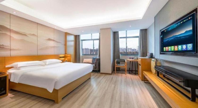 a bedroom with a large bed and a flat screen tv at Jinjiang Metropolo Zhengzhou Songshan Road in Zhengzhou