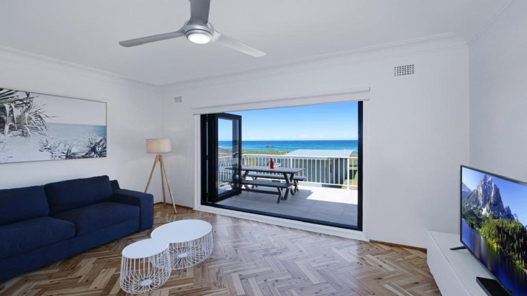 a living room with a blue couch and a view of the ocean at Elanora 3 - Beachfront Unit With Views! in Avoca Beach