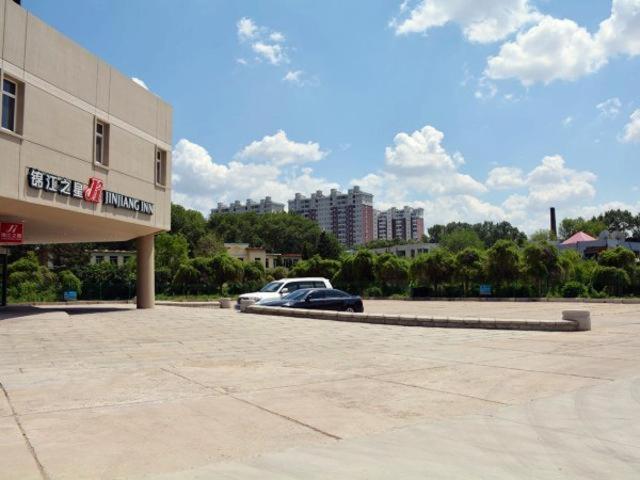 un coche aparcado en un aparcamiento al lado de un edificio en Jinjiang Inn Siping Pingdong Road Wada Square, en Siping