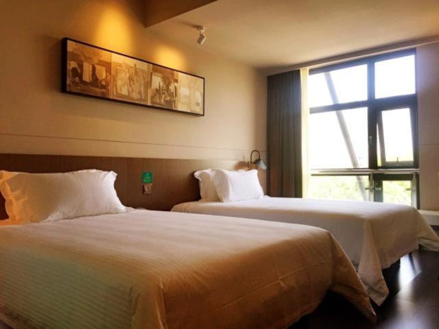 a hotel room with two beds and a window at Jinjiang Inn Select Shanghai International Tourist Resort Huinan Safari Park in Nanhui
