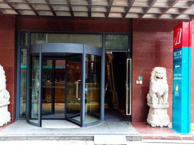 una entrada de cristal a un edificio con una estatua de perro en Jinjiang Inn Hefei Sanxiaokou Lujiang Road en Hefei